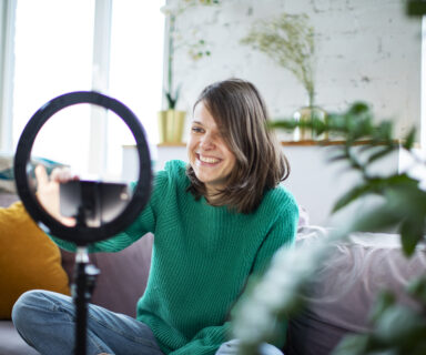 Young influencer woman streaming live video with smartphone and led