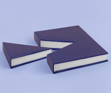 A-minimal-abstract-creative-scene-made-from-a-book-from-which-a-piece-was-cut.-Isolated-pastel-purple-blue-background-with-copy-space.-Cake-slice-concept.-Pleasure-of-reading.-Gift