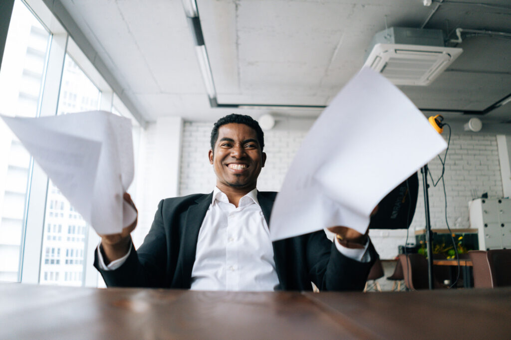 Close-up-low-angle-view-of-angry-African-American-business-man-throwing-up-paper-account-documents-scream-shout
