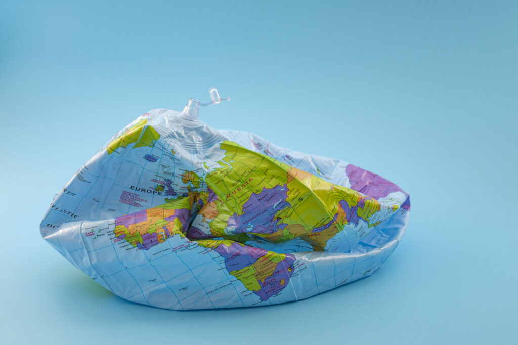 Global-warming-climate-catastrophe-and-environmental-trouble-concept-with-deflated-globe-isolated-on-blue-background