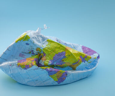 Global-warming-climate-catastrophe-and-environmental-trouble-concept-with-deflated-globe-isolated-on-blue-background