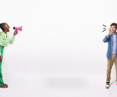 Mature-woman-talking-into-a-megaphone-while-young-man-holds-hand-to-ear-listening