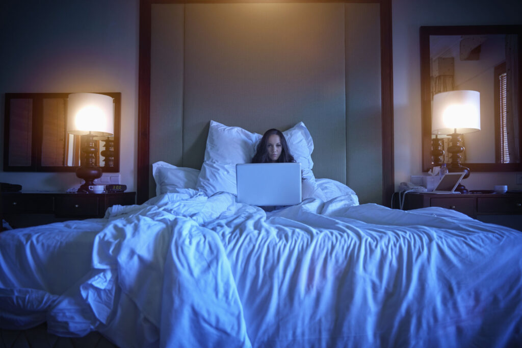 Pacific Islander woman using laptop in bed
