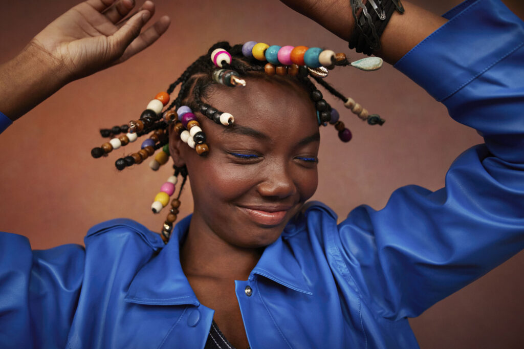 Smiling teenage girl wearing blue jacket shaking head against brown background