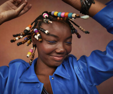 Smiling teenage girl wearing blue jacket shaking head against brown background