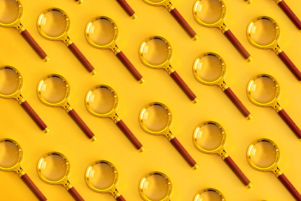 Top-view-of-pattern-magnifying-glass-on-a-pastel-yellow-background.-Space-for-your-text.
