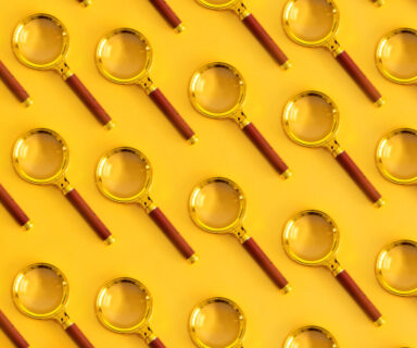 Top-view-of-pattern-magnifying-glass-on-a-pastel-yellow-background.-Space-for-your-text.