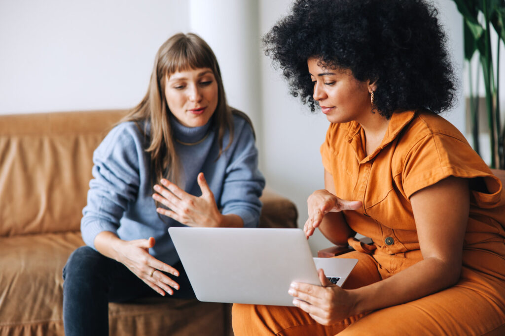 Two-businesswomen-having-a-discussion-while-looking-at-a-laptop-screen