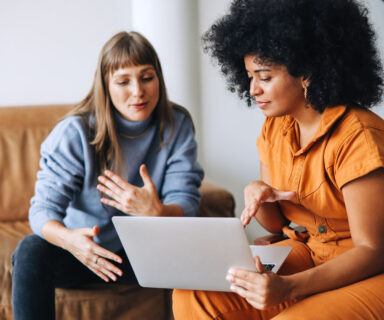 Two-businesswomen-having-a-discussion-while-looking-at-a-laptop-screen